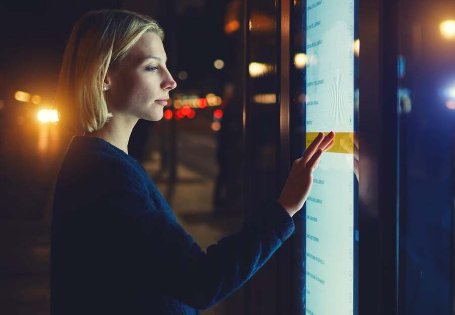 A woman interacts with an outdoor digital signage wall.