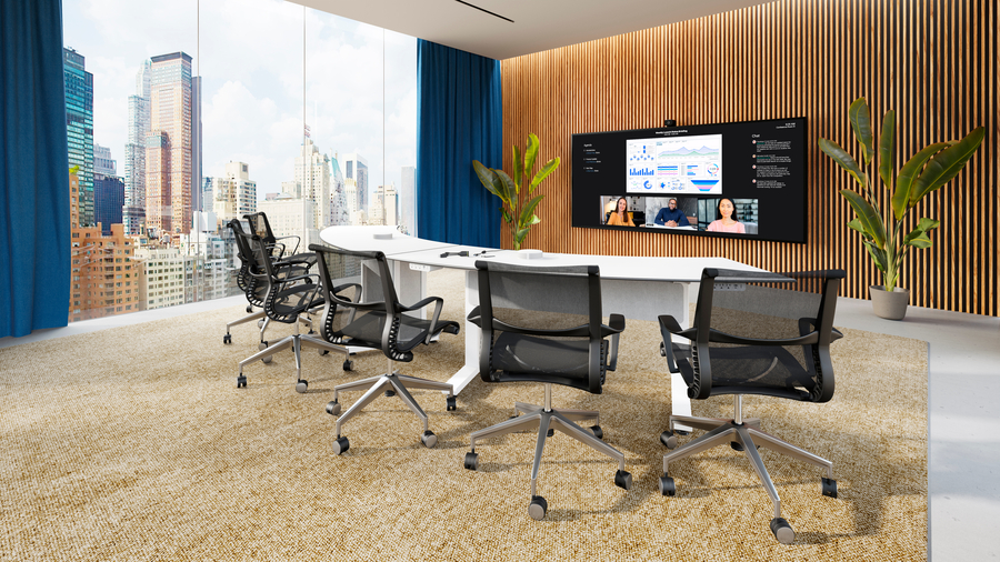 A modern conference room with a curved table facing a video display and a city skyline visible through the window.