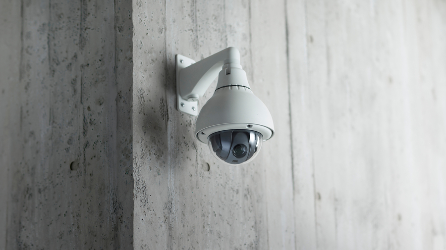 A dome surveillance camera mounted on a concrete wall.